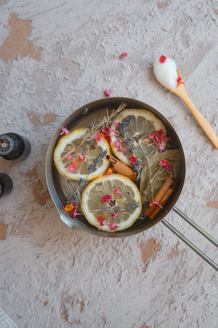 Top view of a bowl with lemon slices, herbs, and spices for aromatic infusion.